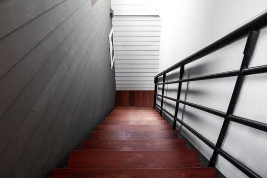 Indoor interior staircase with dirty wooden steps and black handrail