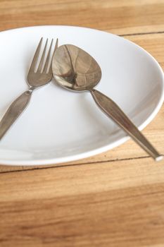 Spoon and fork on white round plate