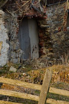 Abandoned uncultivated hut behind tree and fence