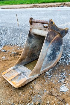 Slim spare shovel of an excavator placed on a construction site next to a new road being built