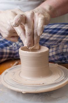 Hands of a potter, creating an earthen jar on the circle