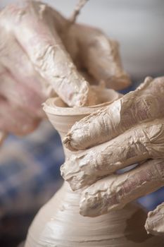 Hands of a potter, creating an earthen jar on the circle