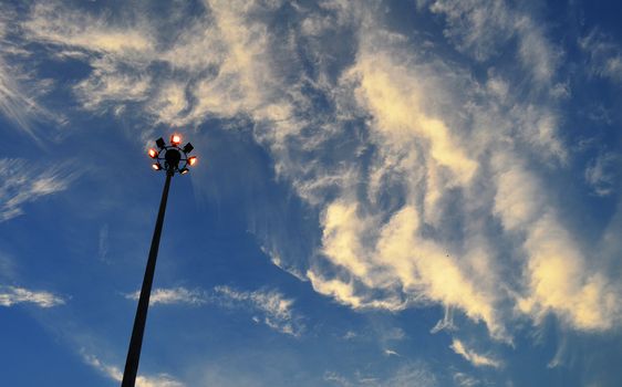 Electricity Spotlight Post in City, Silhouette on Cloudy Blue Sky, in Evening