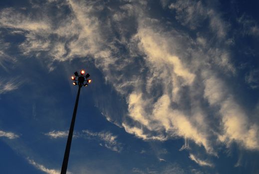 Electricity Spotlight Post in City, Silhouette on Cloudy Deep Blue Sky, at Evening