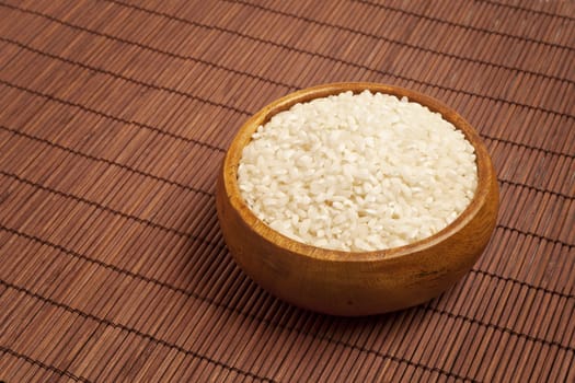 White rice in a wood bowl over bamboo tablecloth