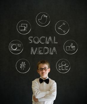 Thinking boy dressed up as business man with social media icons on blackboard background