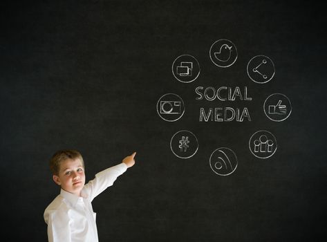 Pointing boy dressed up as business man with social media icons on blackboard background