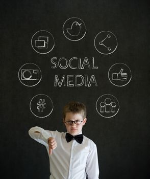 Thumbs down boy dressed up as business man with social media icons on blackboard background