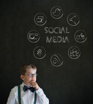 Thinking boy dressed up as business man with social media icons on blackboard background