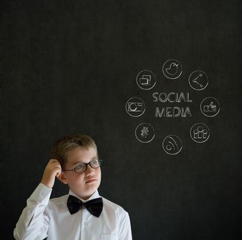 Thinking boy dressed up as business man with social media icons on blackboard background