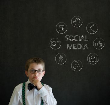 Thinking boy dressed up as business man with social media icons on blackboard background