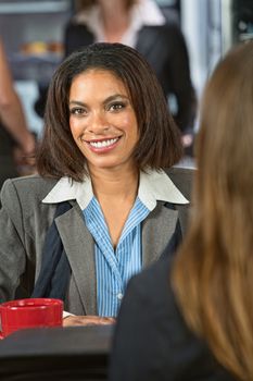Smiling Black woman talking with friend in cafeteria