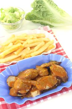 Currywurst with french fries with salad on a light background