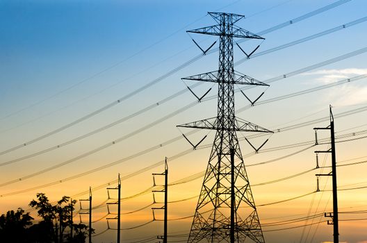 High-voltage electrical transmission towers with sunset background.