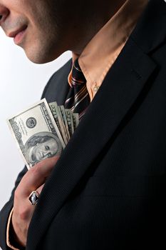 Close up of a business mans hand hiding money in his suit jacket pocket.