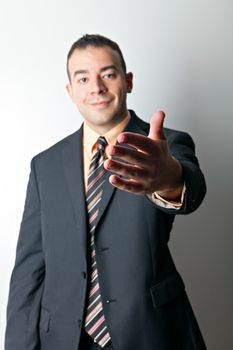 Friendly business man greeting the viewer and extending his hand out for a handshake. Shallow depth of field with focus on the hand.
