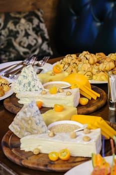 banquet table, various cheeses on wooden plate, profiteroles