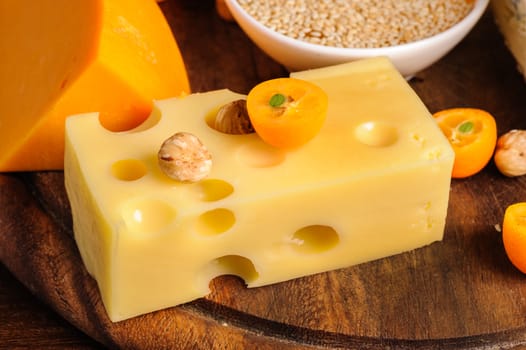 various cheeses with nuts and fruits on wooden plate