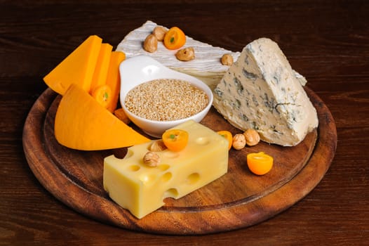 various cheeses with nuts and fruits on wooden plate