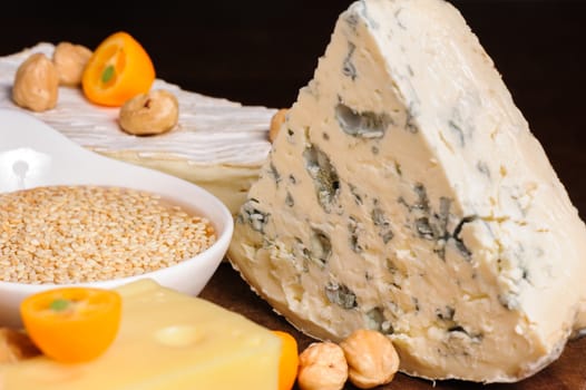 various cheeses with nuts and fruits on wooden plate