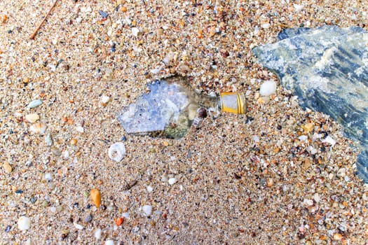 Bottle thrown out by the sea on the beach.