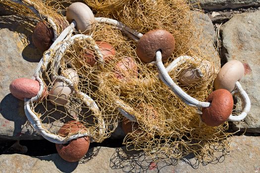Close up of fishing net with ropes and floats in the harbor on a stone background