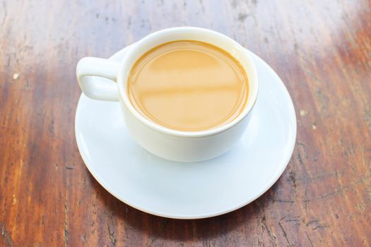 A coffee with a white cup on wooden background.