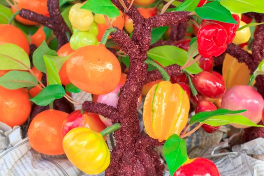 Many fake fruit hanging on the fake tree.