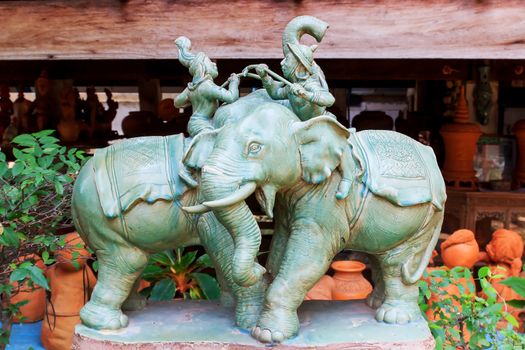 2 elephant statues are fought by people riding.