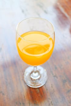 Glass of fresh orange juice on a vintage wooden background.