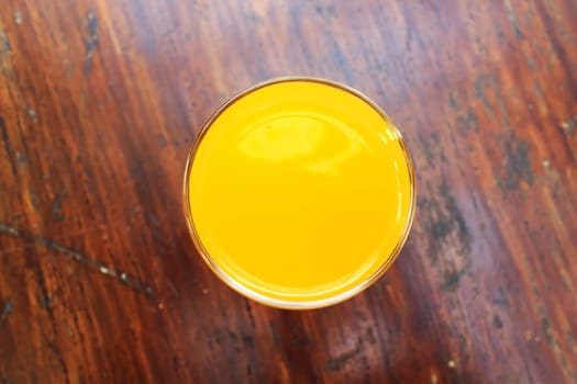 Glass of fresh orange juice on a vintage wooden background.