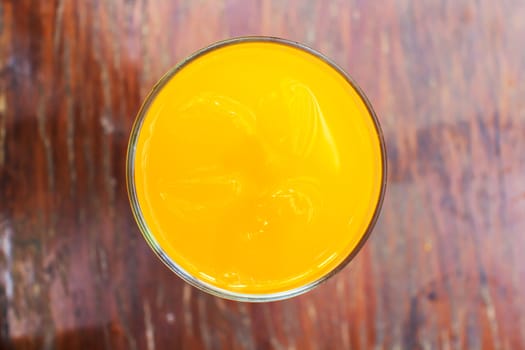Glass of fresh orange juice on a vintage wooden background.