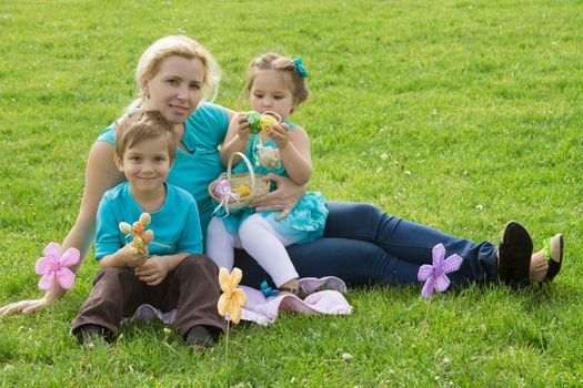 Lovely mother and little boy and girl in green grass