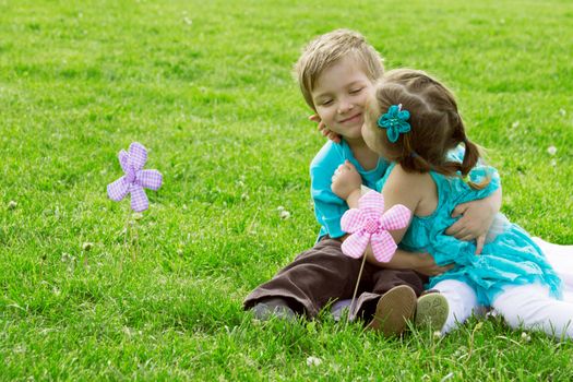 Happy little boy and girl kissing in green grass