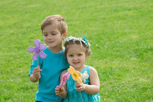 Happy sister and brother playing with flowers in green grass