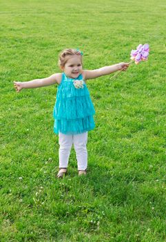 Happy little girl among green meadow with flowers
