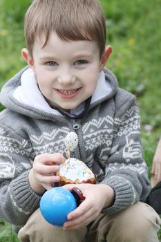 Happy boy with Easter eggs and cake outdoor