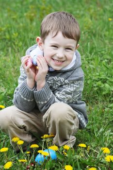 Happy boy with eastre egg among spring garden