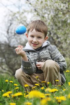 Happy boy with eastre egg among spring garden