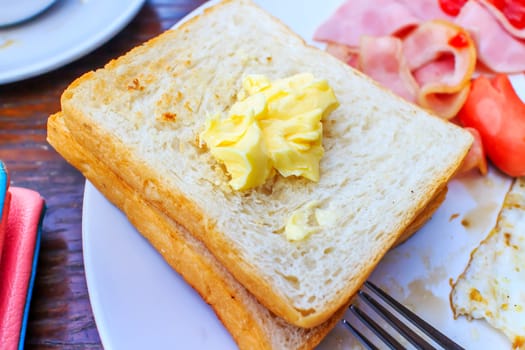 The toast topped with butter in white dish.
