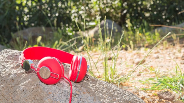 Bright red wired headphones on the rock with free place for your text