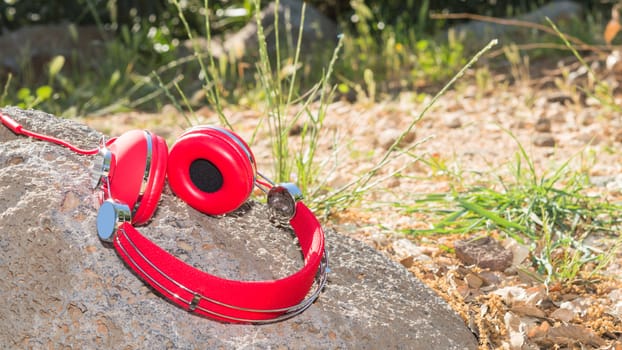Vivid red wired headphones on the stone with free area for your text