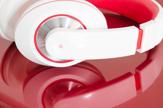 Red and white colorful headphones on bordo laptop mirrored surface