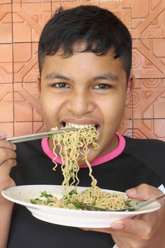 Thai teen boy eating noodle