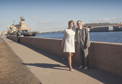 couple walk along the embankment of the river