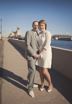 couple walk along the embankment of the river