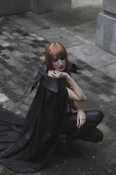 Dark beauty under rain, red hair woman with long black coat