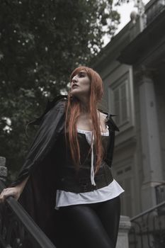 Dark beauty under rain, red hair woman with long black coat