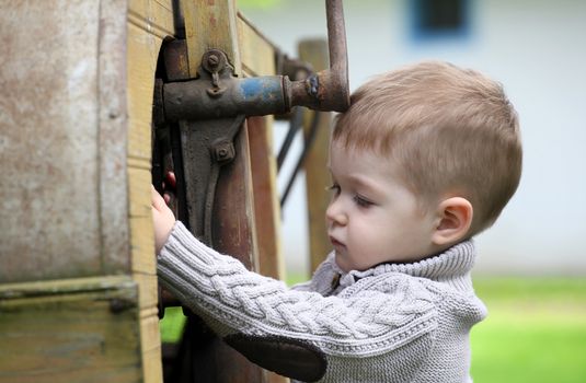 2 years old curious Baby boy managing with old agricultural Machinery