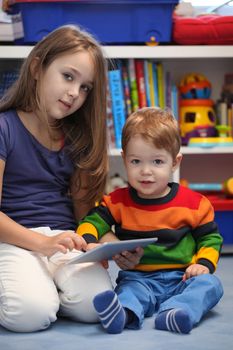 Girl with her little brother fun using a digital tablet computer